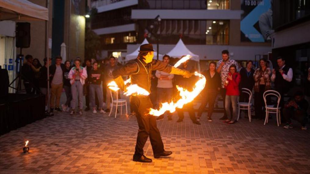 Performer twirling fire at Block Party event at Footscray Park campus while crowd watches