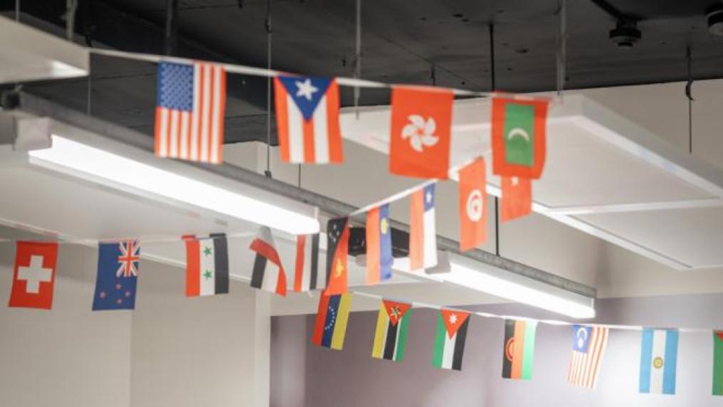 A variety of different countries' flags hanging from the ceiling.
