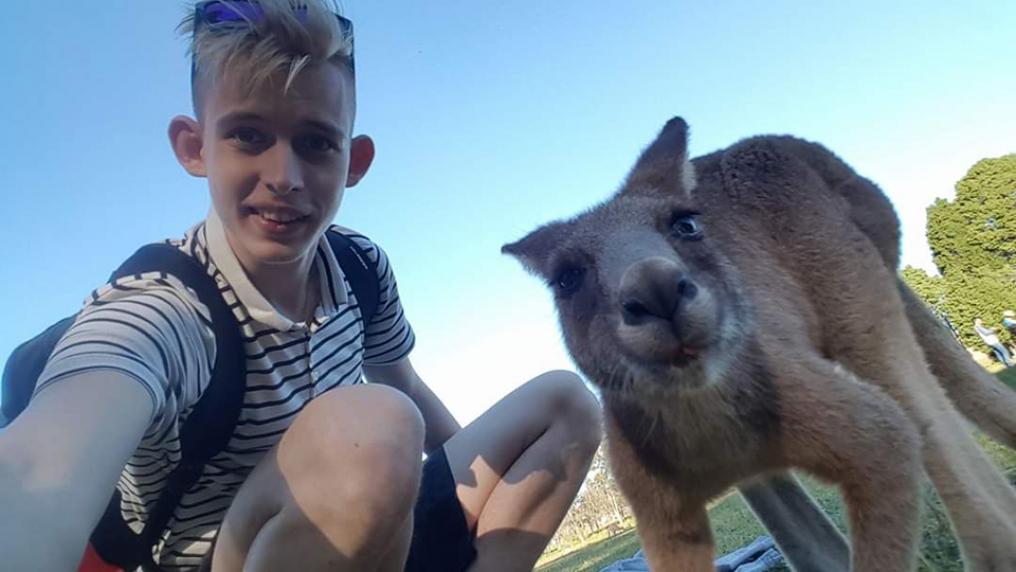 Denis squats to take a selfie with a kangaroo