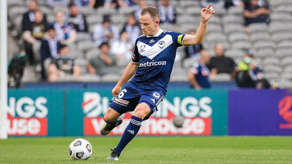 Leigh Broxham in a stadium poised to kick a soccer ball, one arm in the air