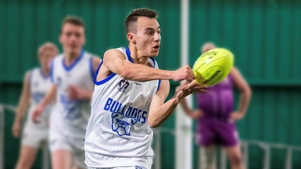 Steve Obeid handballing a football in a Bulldogs singlet
