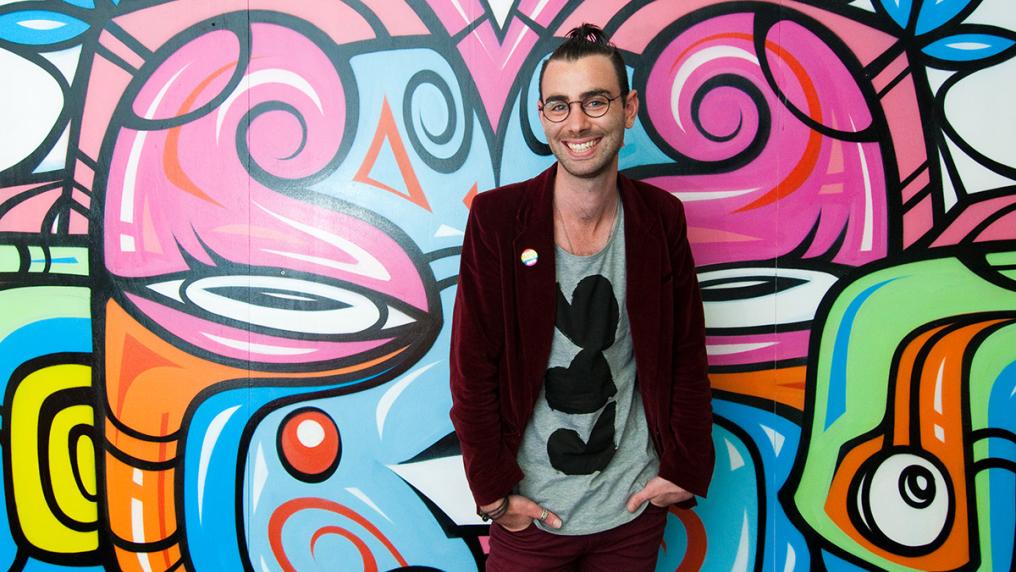 Young man in on-trend clothing, in front of graffiti wall