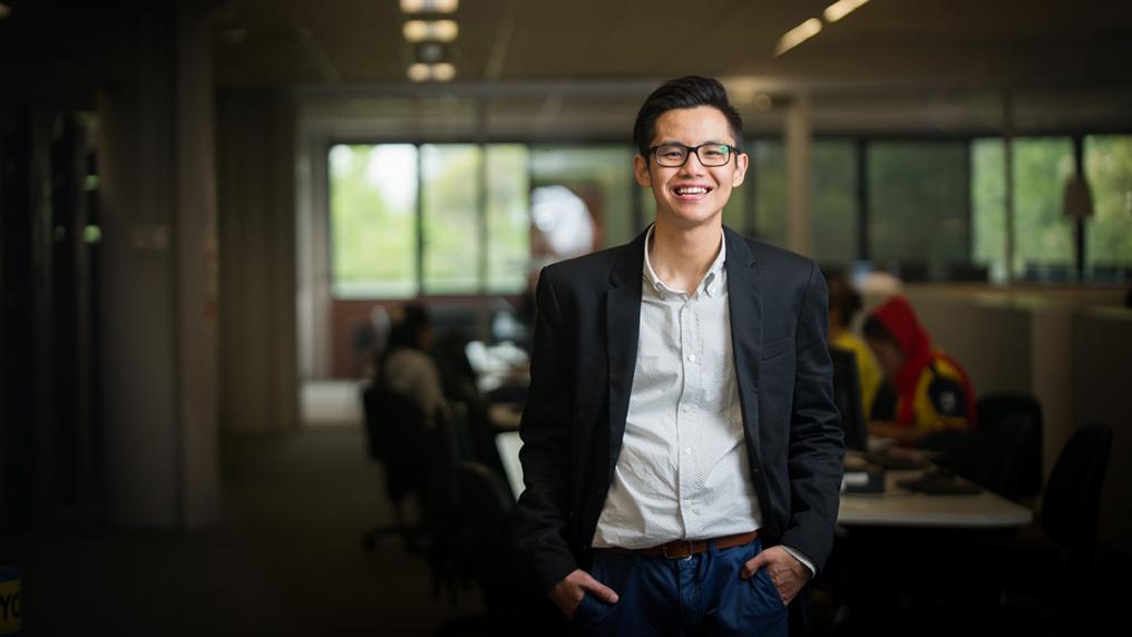 Asian man in blazer smiles at camera in adult education setting