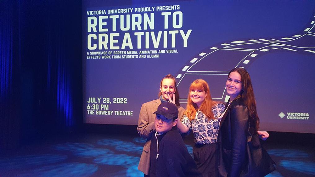 VU Bachelor of Screen Media students stand in front of a screen schowcasing details for Return to Creativity at the Bowery Theatre.