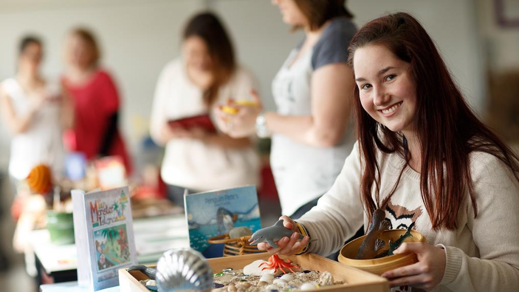 Young woman works with education play set up in small class setting