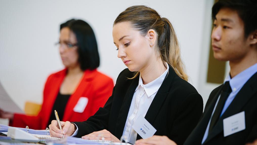 3 students seated, attentive during a MOOT.