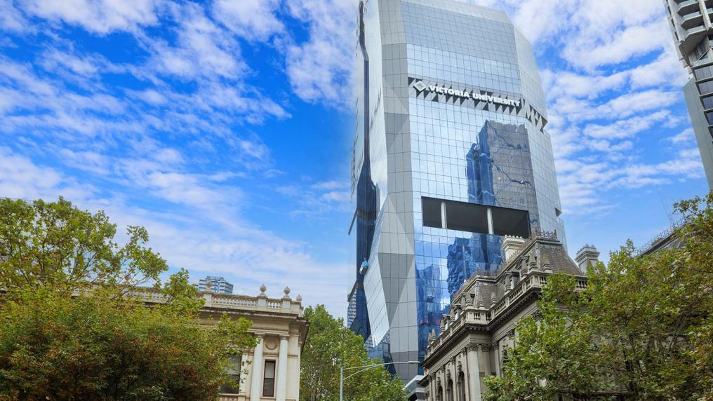 view from the street looking up at the city tower with leafy trees at the bottom of picture with blue sky and clouds surrounding it
