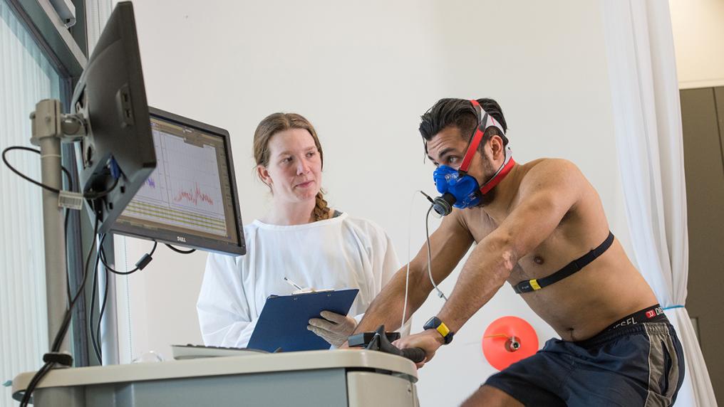 A health and sport researcher works with a participant who trains on an exercise bike.