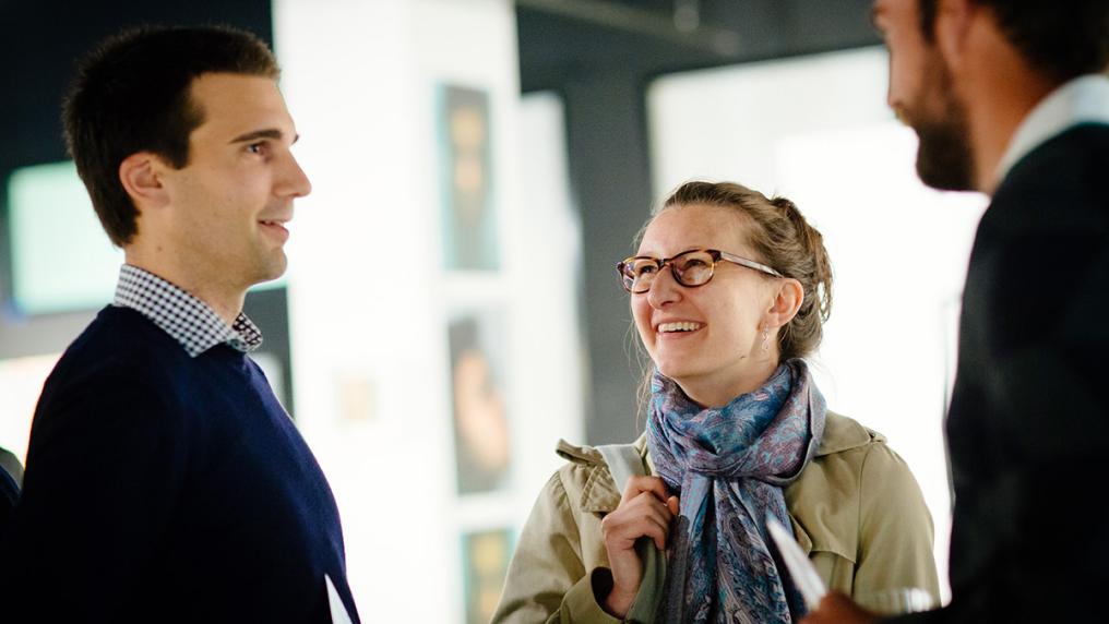 3 adults smile and chat in formal setting