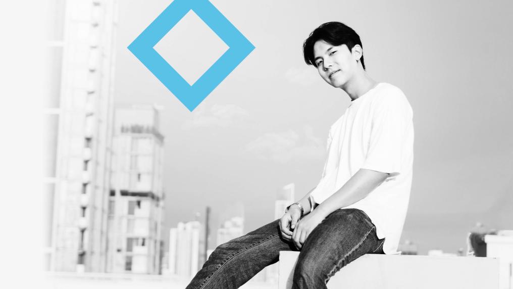 A student sits on a concrete step with skyscrapers and the VU blue branded diamond in the background.