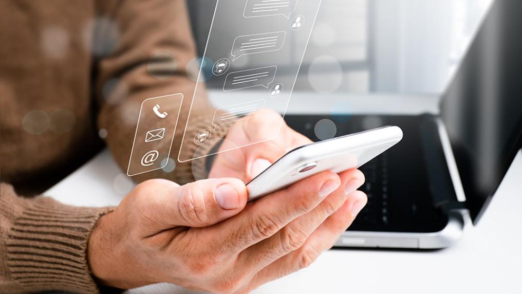 A person holds a phone, using generative AI, while sitting in front of a laptop.