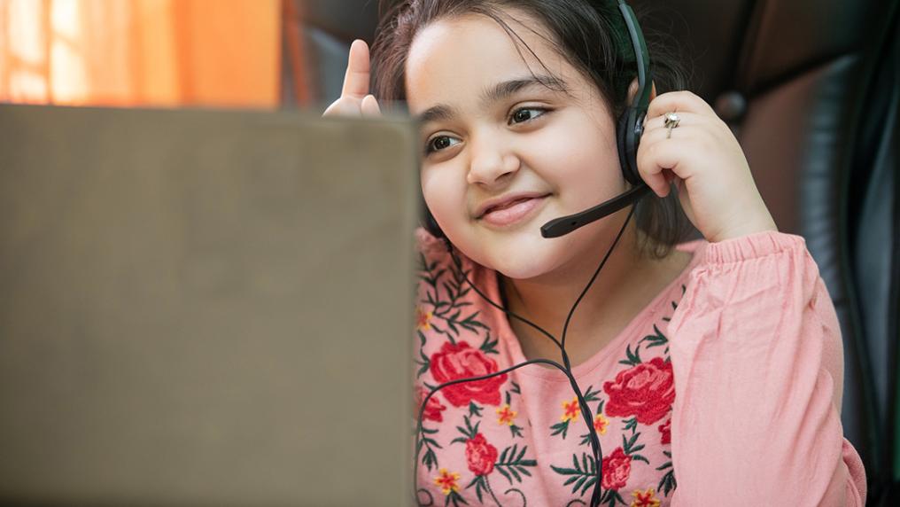 Young girl with a headset on learning remotely