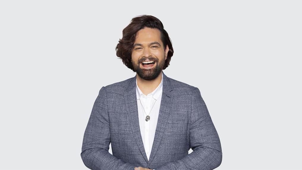 Dylan standing in front of a blank background, smiling at camera.