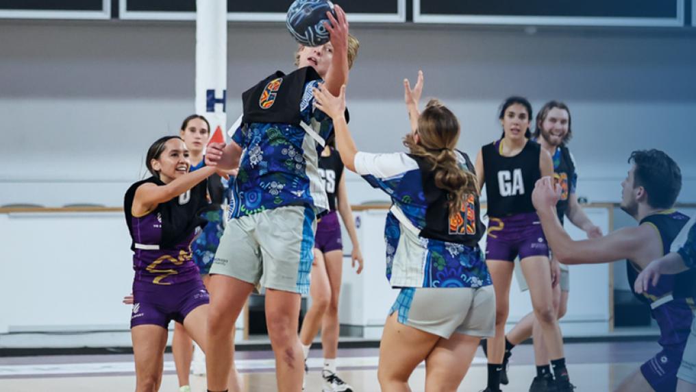 Young men and women play netball in colourful uniforms