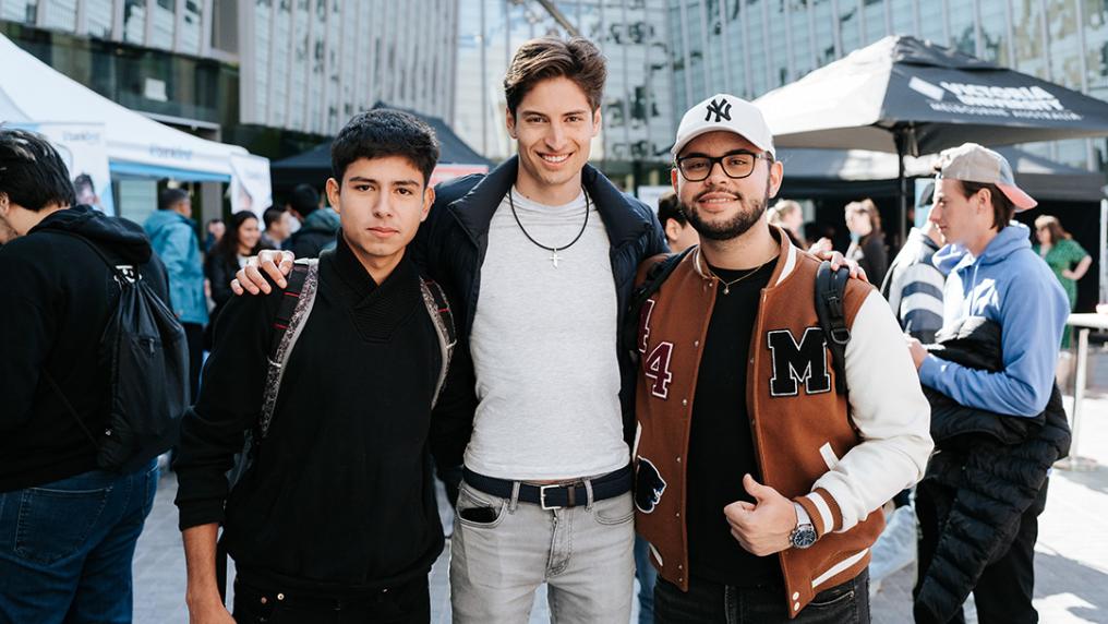 3 young men smile at the camera at an on campus event