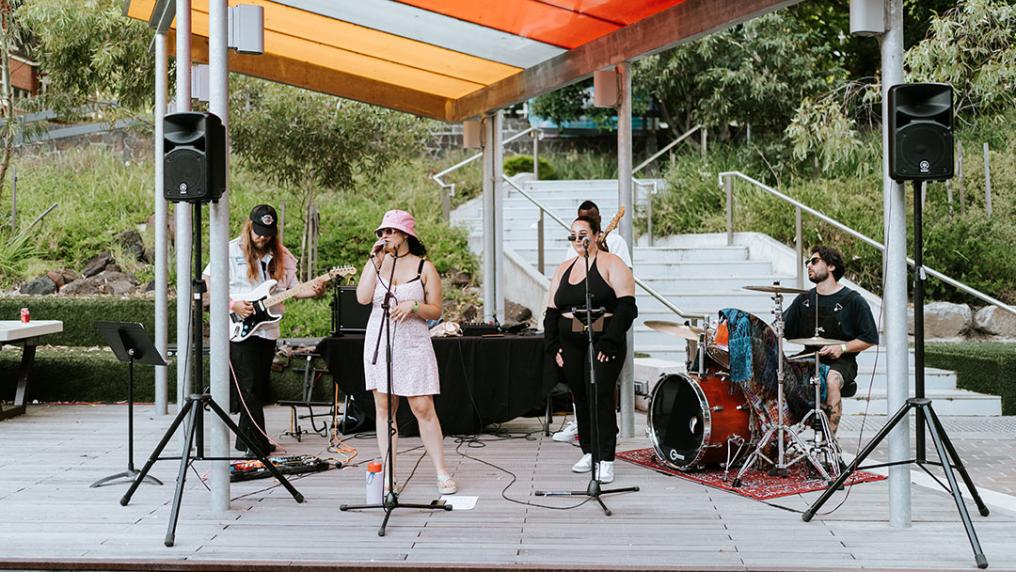 Band of young musicians perform on campus, with singing electric guitar and drums