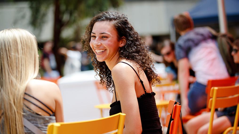 Female student seated outside enjoying O-Fest activities at Footscray Park campus.