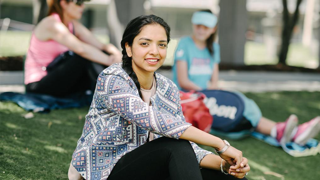 Indian international student, Preeti Bhandurge sits on a grassy slope.