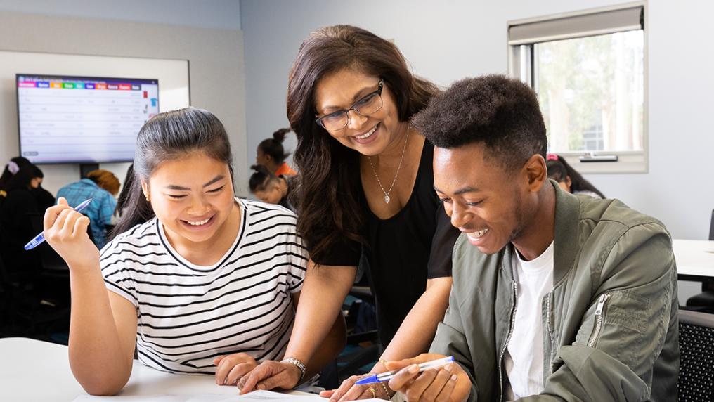 A teacher in a classroom helping out students.