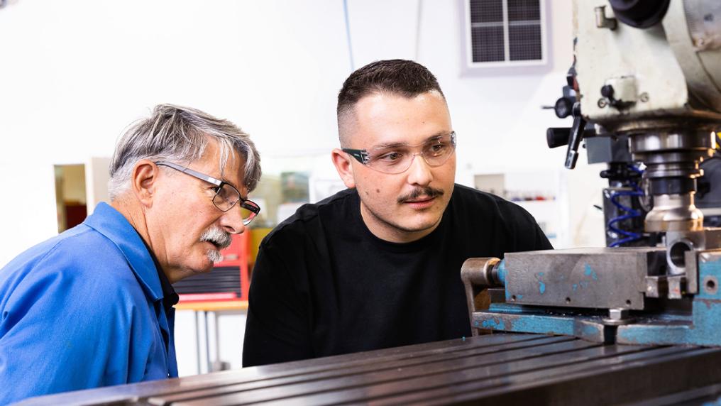 A TAFE student and teacher learning about machinery.