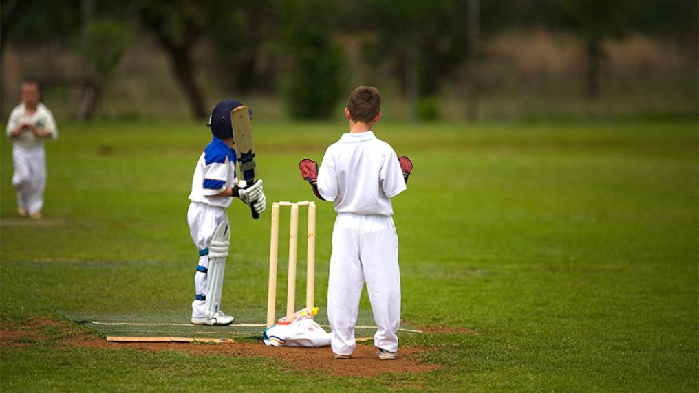 Kids playing cricket outside.