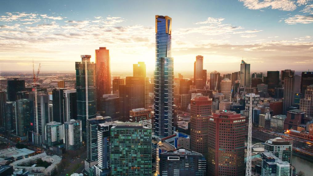 An view of Melbourne City landscape from high up at sunset. In the middle of the photo is a tall skyscraper, the Melbourne Skydeck.