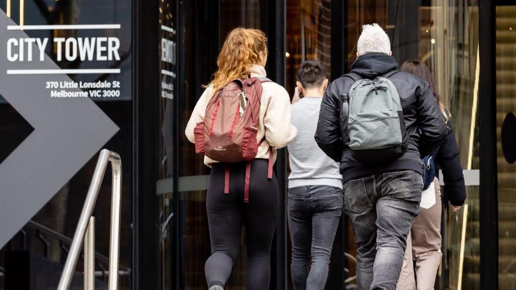 A group of students walking into a building. A sticker on the building says "City Tower"
