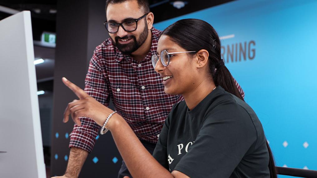 A smiling woman receives advice for computer-based work