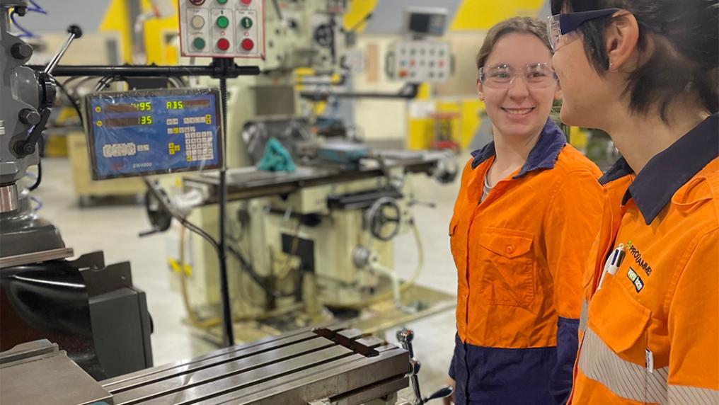 Two young people in tradie shirts in an engineering lab