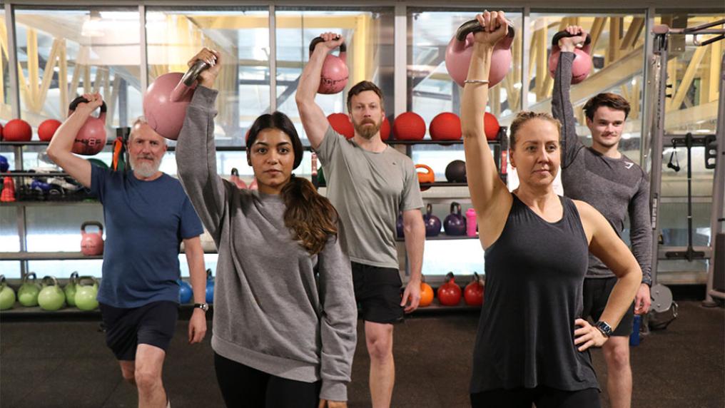 Gym goers holding up kettlebells during a training session at Footscray Park Campus gym.