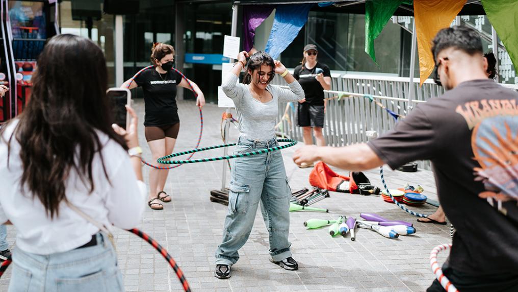 A group of young people hoola-hooping in a university courtyard