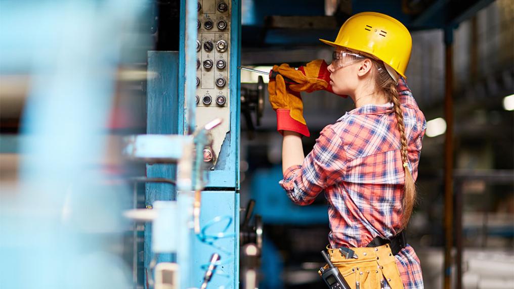 A female electrician in a yellow hard hat at work.