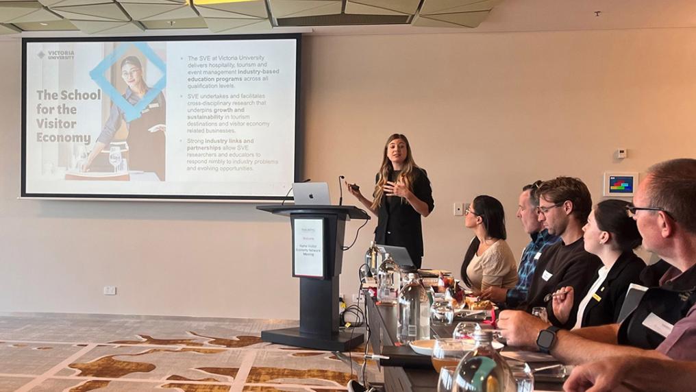 A young woman presents to a room of professional-looking attendees