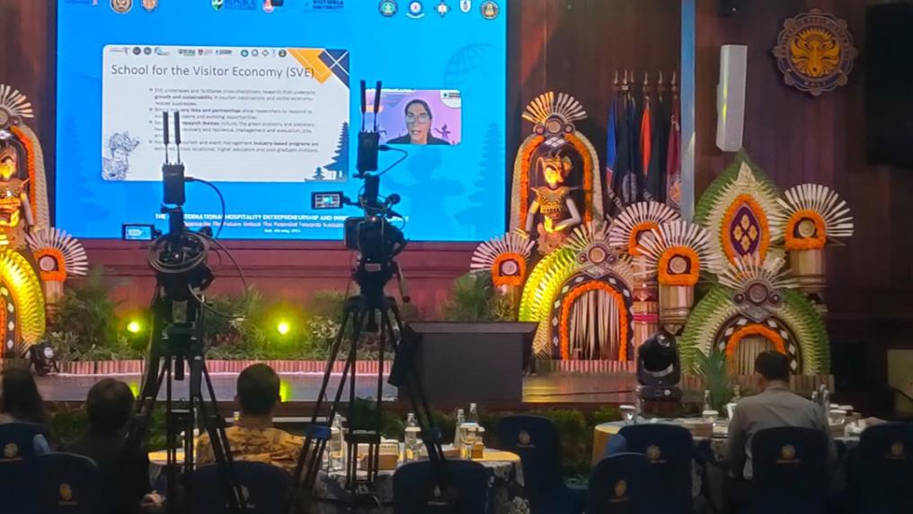 A stage adorned with bright green, orange and white decorative sculptures in front of a presentation screen