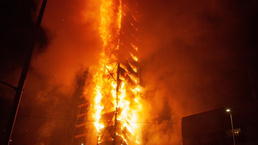 A fire burning throughout a tall skyscraper building.