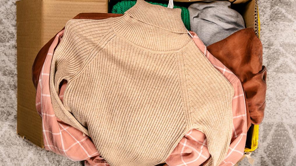 Clothing piled on top of an open cardboard box.