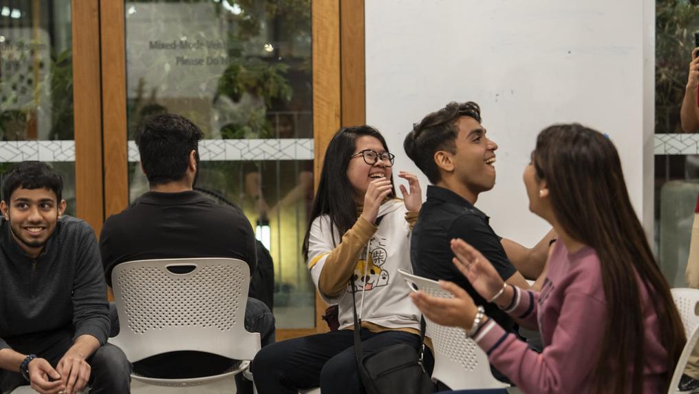 A multicultural group of young people laugh while enjoying a conversation