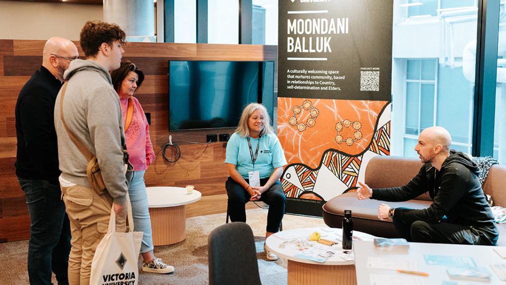 Moondani Balluk stall with two VU staff talking to a family
