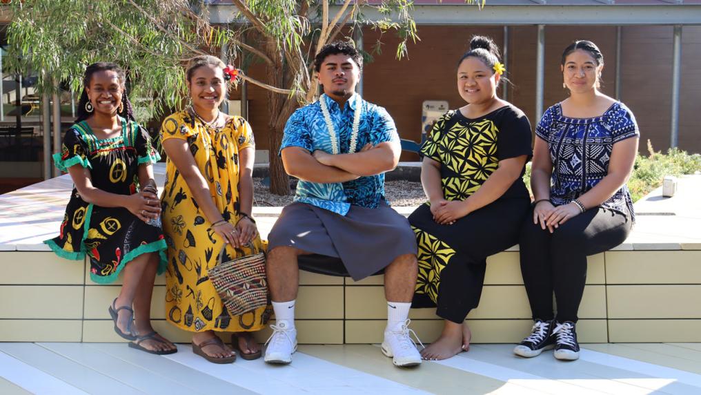 Five students sitting outside smiling at the camera