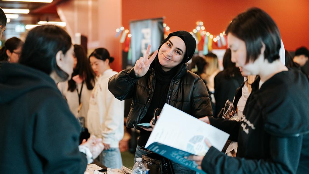 Young female student at City Campus holding up fingers in peace sign