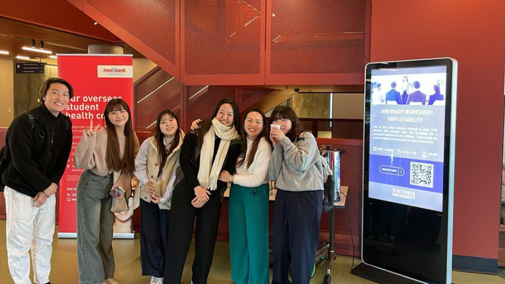 A group of international students smile and pose in a bright modern foyer