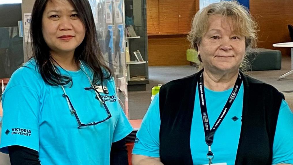 Two people in VU t-shirts standing in the VU Library.