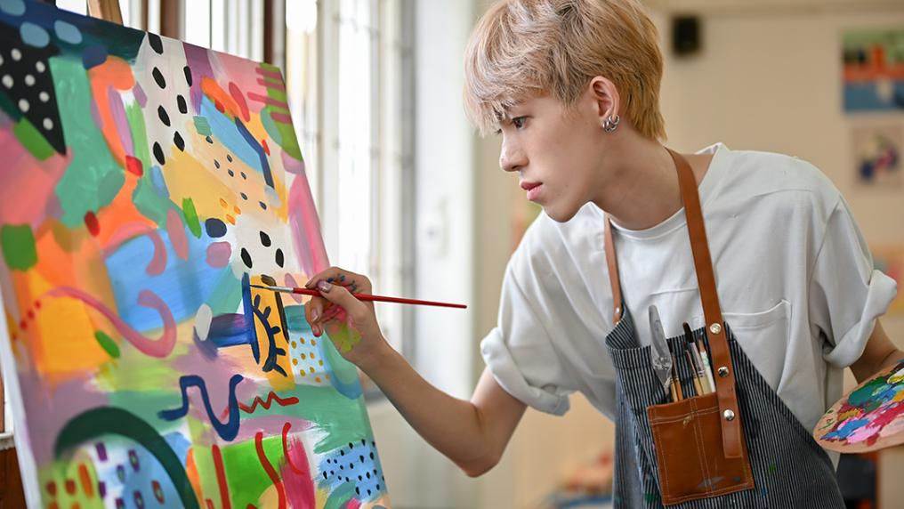 A young person paints a colourful artwork
