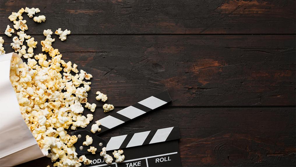 Popcorn and clapper against a brown background.