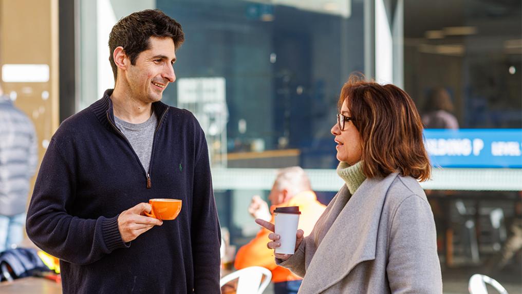 Staff members having coffee outside the Reading Room at Footscray Park campus.