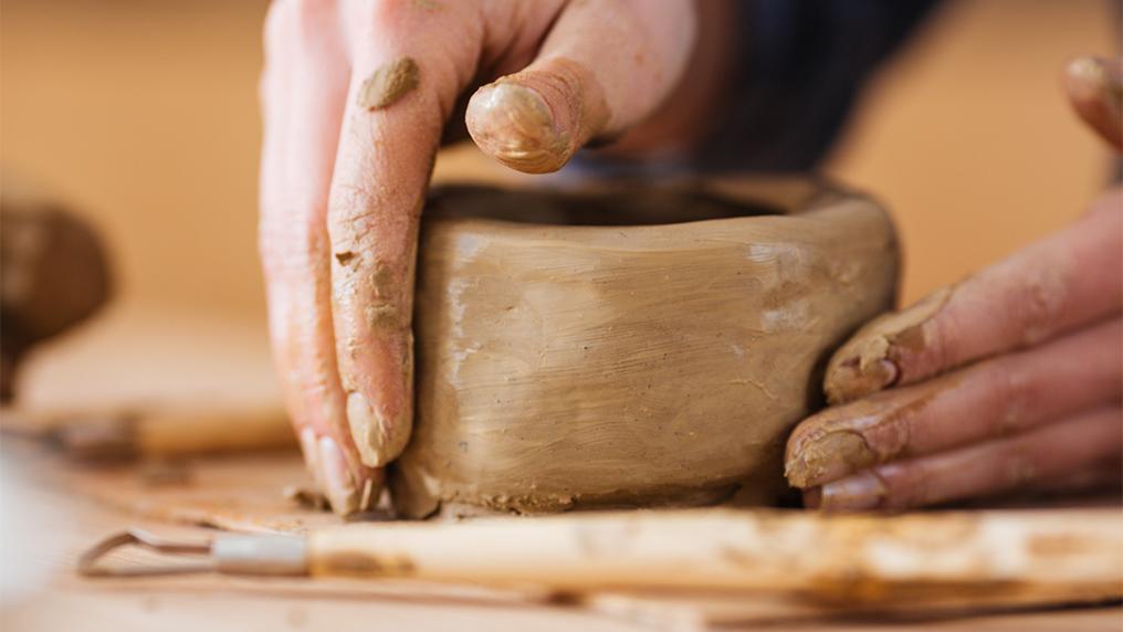 Hands making a clay bowl.