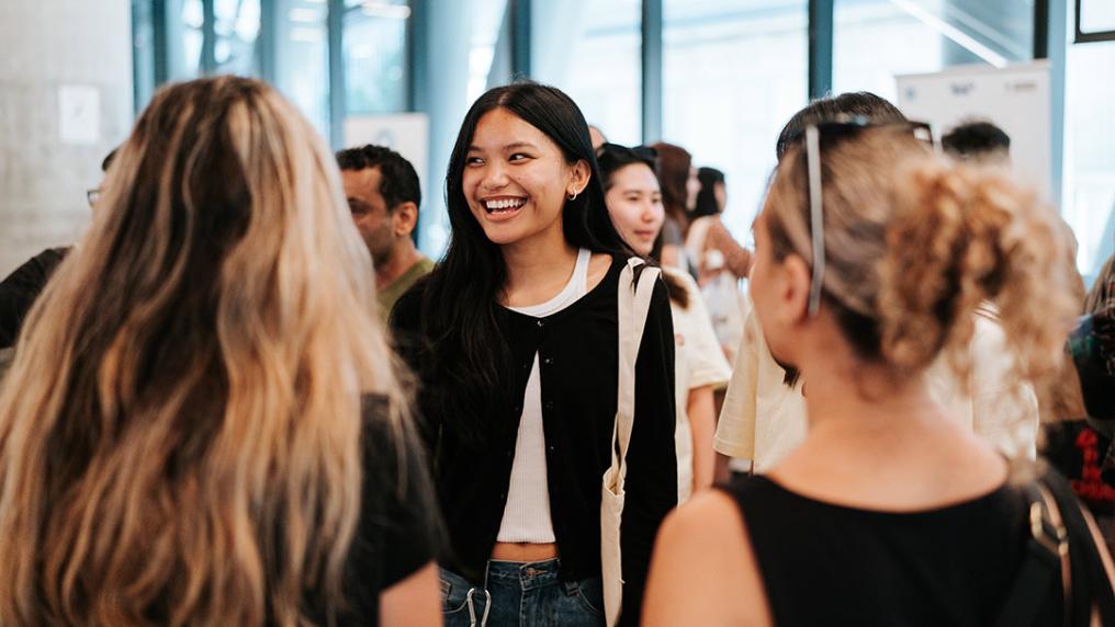 A group of young people interact happily in a bright, modern building
