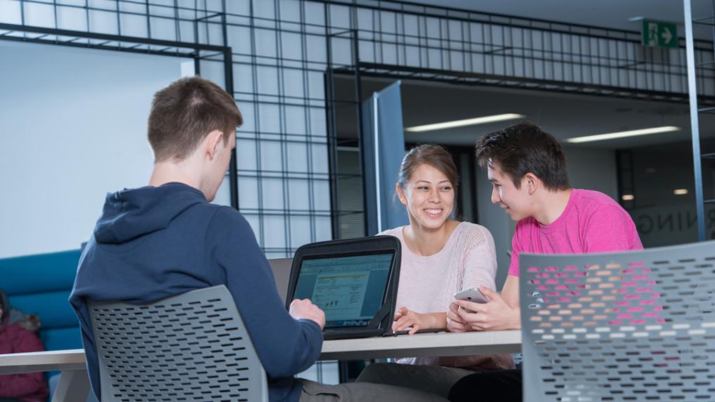 A group of students at with computers work in a modern library