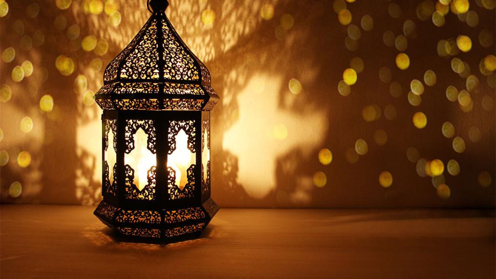 Intricate lamp lit and casting beautiful shadows and patterns on a wall.