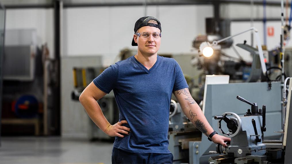 VU trades student poses in front of machinery. 